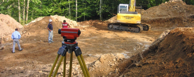 Ingeniero midiendo pendientes y niveles del terreno con equipo topográfico.