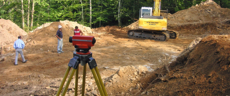 Ingeniero midiendo pendientes y niveles del terreno con equipo topográfico.